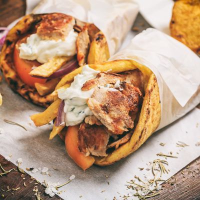 Greek gyros wraped in a pita bread on a wooden background