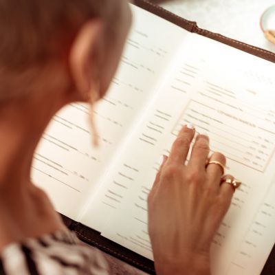 Reading the menu. Top view of woman wearing nice rings reading the menu in restaurant sitting at summer terrace