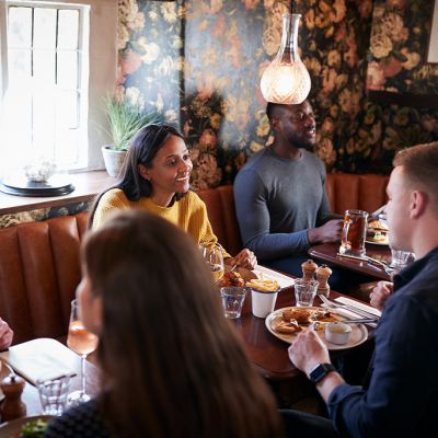 Group Of People Eating In Restaurant Of Busy Traditional English Pub