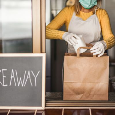 Young woman preparing takeaway healthy food inside restaurant during Coronavirus outbreak time - Worker inside kitchen cooking vegetarian food for online order service - Focus on salad