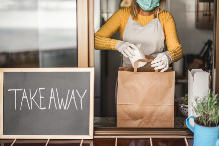 Young woman preparing takeaway healthy food inside restaurant during Coronavirus outbreak time - Worker inside kitchen cooking vegetarian food for online order service - Focus on salad