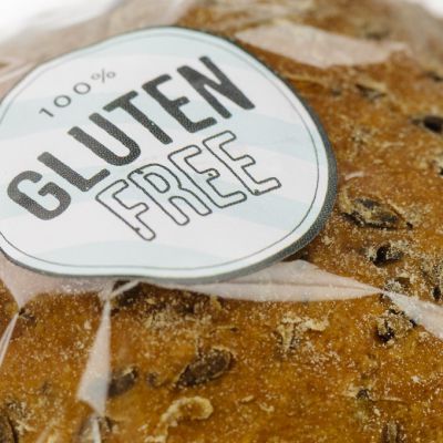 "100% Gluten Free" sticker on a loaf of brown seeded bread.