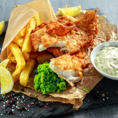 British Traditional Fish and chips with mashed peas, tartar sauce on crumpled paper