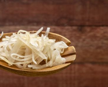 sauerkraut (fermented cabbage) on a wooden spoon against rustic barn wood background, probiotics concept - fermented food good for gut health, panoramic web banner