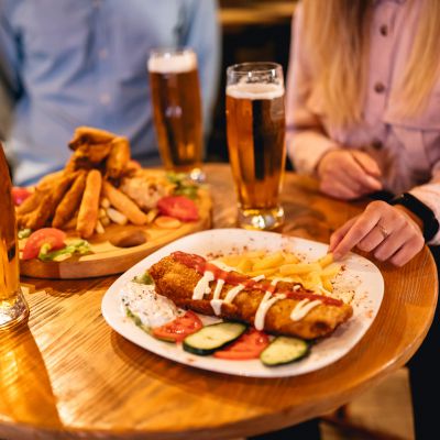 Small group of young Caucasian friends having a nice time talking, drinking beer and eating pub food.