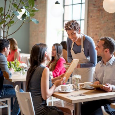 Friendly waitress serving couple at a restaurant taking orders and looking very happy