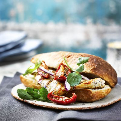 Chicken ciabatta ona table with platesa and napkins