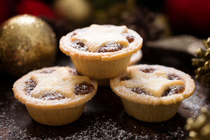 Three powdered mince pies with star tops on a festive background. Three powdered mince pies with star tops on a festive background.